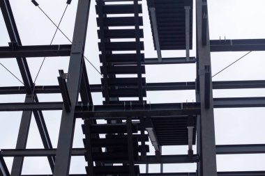 Şehir inşaatı için modern mimari, yapı mühendisliği ve endüstriyel tasarım elementlerinin sergilendiği kirişleri, çapraz destekleri ve merdiven platformları olan endüstriyel çelik iskelet.