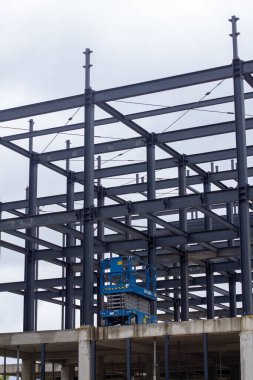 Şehir inşaatı için modern mimari, yapı mühendisliği ve endüstriyel tasarım elementlerinin sergilendiği kirişleri, çapraz destekleri ve merdiven platformları olan endüstriyel çelik iskelet.