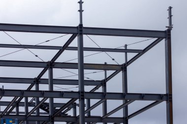 Şehir inşaatı için modern mimari, yapı mühendisliği ve endüstriyel tasarım elementlerinin sergilendiği kirişleri, çapraz destekleri ve merdiven platformları olan endüstriyel çelik iskelet.