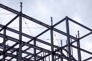 Şehir inşaatı için modern mimari, yapı mühendisliği ve endüstriyel tasarım elementlerinin sergilendiği kirişleri, çapraz destekleri ve merdiven platformları olan endüstriyel çelik iskelet.