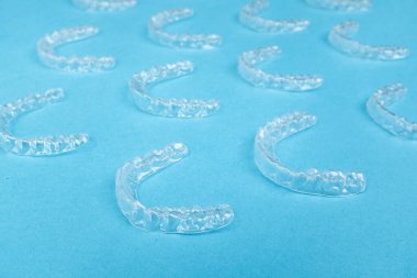 Renkli bir arka planda şeffaf plastik diş hizalayıcıları. Ortodontik silikon çalıştırıcı dikey pankart. Görünmez diş teli reklamı. Tıbbi web konsepti. Artıları, eksileri hizala.