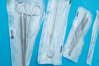 Steril diş aletleri ve araçları mavi arka plandaki ayrı keselerde mühürlendi