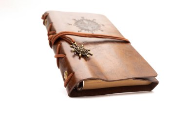  Bej kağıdın üzerinde duran gerçek deriden yapılmış el yapımı bir günlük. Ahşap arka planda eski bir deri kitap. Kahverengi deri kapaklı el yapımı kağıt günlük defteri.