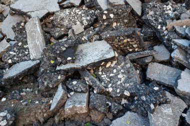 Kırık beton ve asfalt moloz yığını, inşaat alanının yıkıntıları, ezilmiş taş ve betonun kaba dokusu, yol üstüne atık madde veya bina tahribatı.