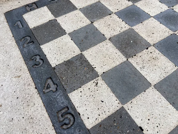Kalıcı Açık Satranç tahtası, beton kaldırım yüzeyinde cebirsel gösterimi olan siyah beyaz taş kareler, halka açık park oyun konsepti