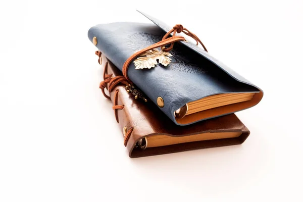 Beyaz arka planda kabartmalı dizaynlı iki adet eski deri dergi yığını