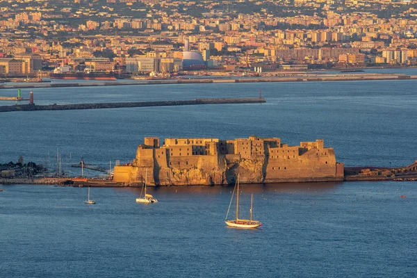 Napoli Körfezi 'ndeki küçük bir adadaki tarihi Castel Dell' Ovo kalesinin altın saat manzarası. Şehir manzarası ve yelkenli tekneleri var.