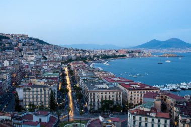 Napoli rıhtım şehri Akdeniz limanı üzerinde gün batımında kentsel yoğunluk kıyı manzarasını betimliyor.