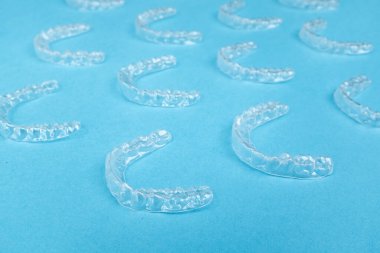 Renkli bir arka planda şeffaf plastik diş hizalayıcıları. Ortodontik silikon çalıştırıcı dikey pankart. Görünmez diş teli reklamı. Tıbbi web konsepti. Artıları, eksileri hizala.