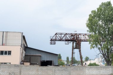 Bulutlu gökyüzünün altındaki sanayi binasının yanındaki paslı vinç