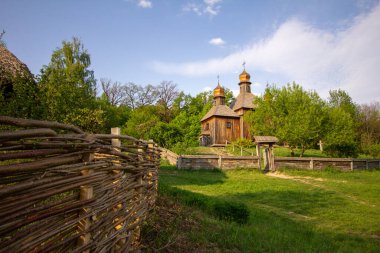 Ağaçlar ve yeşil otlarla çevrili ahşap kilise.