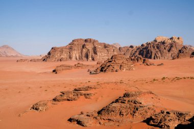 Uçsuz bucaksız çöl manzarası kayalık dağlar ve berrak gökyüzü.
