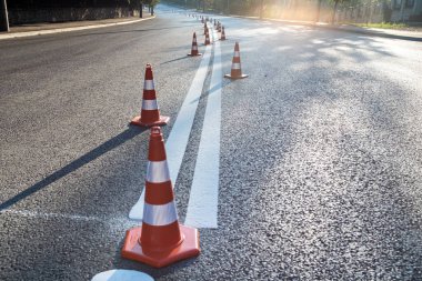 Trafik konileri yolu güneş ışığıyla aydınlatıyor.