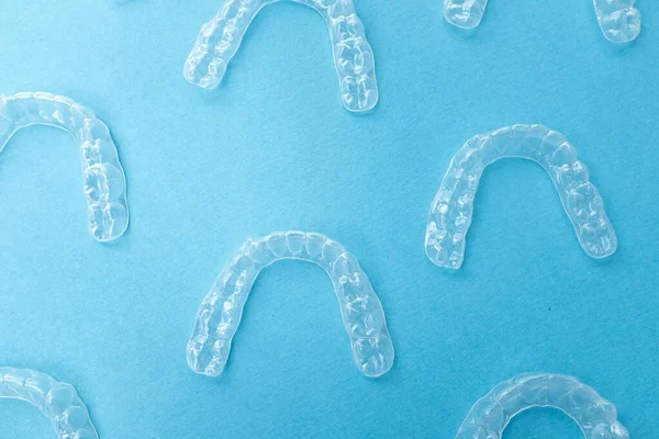 Renkli bir arka planda şeffaf plastik diş hizalayıcıları. Ortodontik silikon çalıştırıcı dikey pankart. Görünmez diş teli reklamı. Tıbbi web konsepti. Artıları, eksileri hizala.