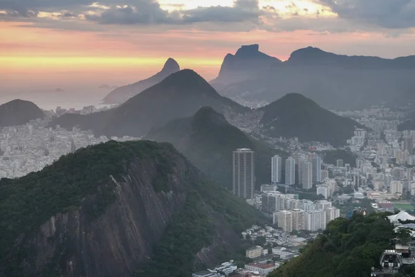 Gün batımında bulutlarla dağların ve şehrin görüntüsü