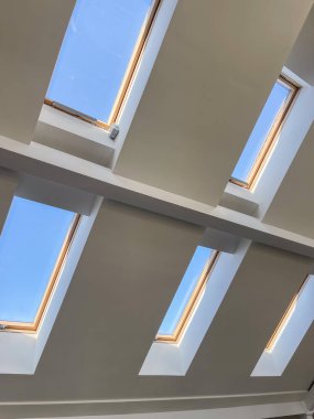 Modern iç mimari, doğal ışık tasarımı ve konut ve ticari kavramlar için parlak tavan arası alanı sergilenen, çağdaş eğimli bir tavana kurulmuş çoklu tavan pencereleri