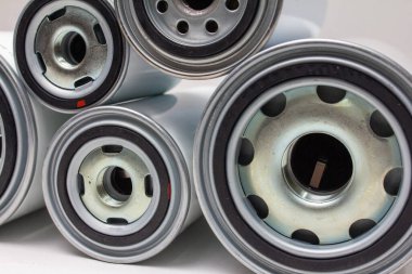 Tarafsız arkaplanda yatay olarak düzenlenmiş birkaç beyaz spin-on yağ filtresi, otomotiv bakım kataloğu veya motor parçaları ekommerce sunumu için ideal temiz ürün görüntüsü.