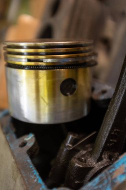 Parçalanmış tek silindir motor veya kompresör, pirinç renkli piston başını, bağlantı çubuğunu ve krankcase açılışını, mekanik onarım ve elden geçirme bağlamını gösterir