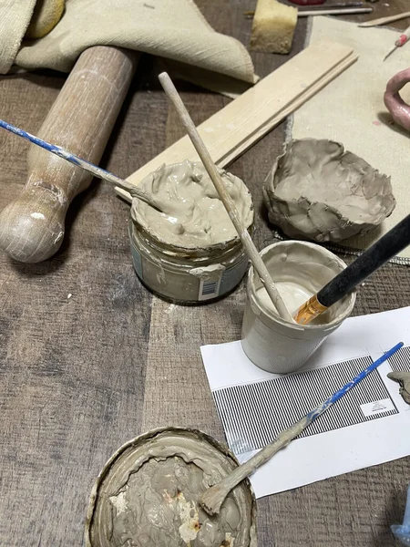 Kil levha yuvarlama ve heykel düzeneği, merdaneler, ahşap çıtalar, oyma araçları, ve çömlek ve seramik el işi için desenli bir çuval bezi yüzeyi üzerinde ham kil topaklar