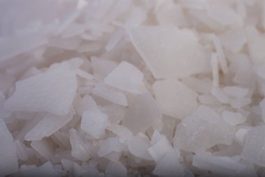 Beyaz arka planda magnezyum tuz tanelerinin yakın çekimi, detaylı beyaz parçacıklar deniz tuzu, doğal desen. Magnezyum terapisi, Sağlık Sigortası, kişisel bakım, sağlığın iyileştirilmesi, ev istirahatı.