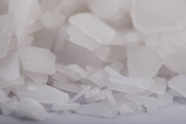 Beyaz arka planda magnezyum tuz tanelerinin yakın çekimi, detaylı beyaz parçacıklar deniz tuzu, doğal desen. Magnezyum terapisi, Sağlık Sigortası, kişisel bakım, sağlığın iyileştirilmesi, ev istirahatı.