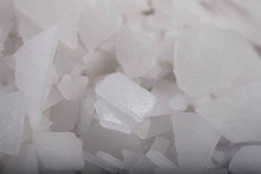 Beyaz arka planda magnezyum tuz tanelerinin yakın çekimi, detaylı beyaz parçacıklar deniz tuzu, doğal desen. Magnezyum terapisi, Sağlık Sigortası, kişisel bakım, sağlığın iyileştirilmesi, ev istirahatı.