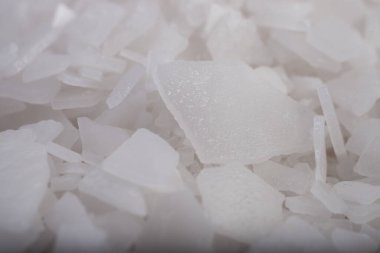 Beyaz arka planda magnezyum tuz tanelerinin yakın çekimi, detaylı beyaz parçacıklar deniz tuzu, doğal desen. Magnezyum terapisi, Sağlık Sigortası, kişisel bakım, sağlığın iyileştirilmesi, ev istirahatı.