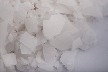 Beyaz arka planda magnezyum tuz tanelerinin yakın çekimi, detaylı beyaz parçacıklar deniz tuzu, doğal desen. Magnezyum terapisi, Sağlık Sigortası, kişisel bakım, sağlığın iyileştirilmesi, ev istirahatı.