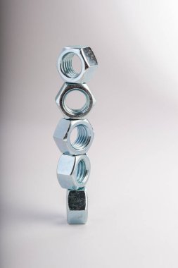 Gri arkaplanda metal fındıkları, mekanik montaj için endüstriyel donanım bileşenleri, bağlanma ve mühendislik kullanımı, inşaat malzemeleri ve hassasiyet üretimi kavramı