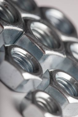Gri arkaplanda metal fındıkları, mekanik montaj için endüstriyel donanım bileşenleri, bağlanma ve mühendislik kullanımı, inşaat malzemeleri ve hassasiyet üretimi kavramı