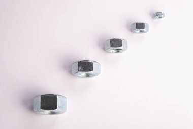 Beyaz zemin üzerinde metal fındıklar, mekanik montaj için endüstriyel donanım bileşenleri, bağlanma ve mühendislik kullanımı, inşaat malzemeleri konsepti ve hassasiyet üretimi