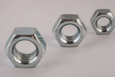 Gri arkaplanda metal fındıkları, mekanik montaj için endüstriyel donanım bileşenleri, bağlanma ve mühendislik kullanımı, inşaat malzemeleri ve hassasiyet üretimi kavramı