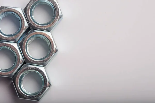 Gri arkaplanda metal fındıkları, mekanik montaj için endüstriyel donanım bileşenleri, bağlanma ve mühendislik kullanımı, inşaat malzemeleri ve hassasiyet üretimi kavramı