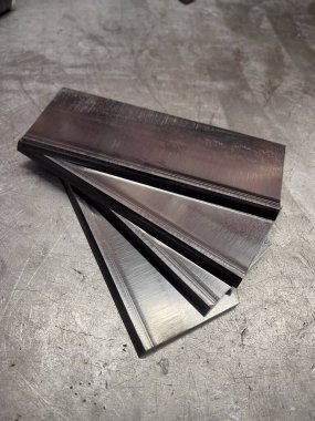 Gri yüzeyde düzenlenmiş önceden kesilmiş çelik parçaları..