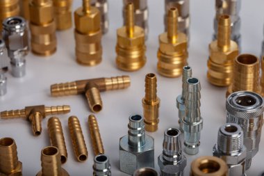 Açık gri arkaplana karşı pirinç hortum ve pnömatik parçaların çeşitliliği