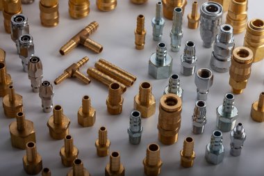 Açık gri arkaplana karşı pirinç hortum ve pnömatik parçaların çeşitliliği