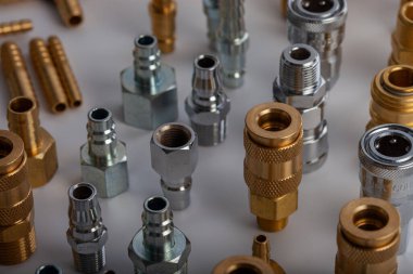 Açık gri arkaplana karşı pirinç hortum ve pnömatik parçaların çeşitliliği