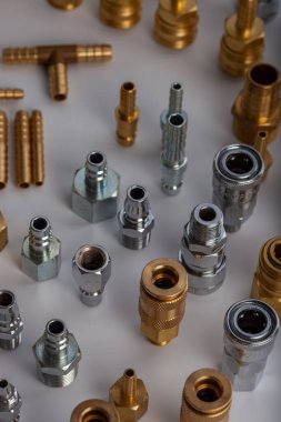 Açık gri arkaplana karşı pirinç hortum ve pnömatik parçaların çeşitliliği