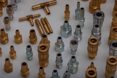 Açık gri arkaplana karşı pirinç hortum ve pnömatik parçaların çeşitliliği