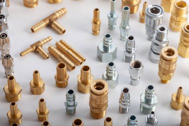 Açık gri arkaplana karşı pirinç hortum ve pnömatik parçaların çeşitliliği