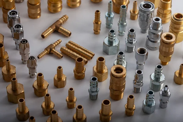 Açık gri arkaplana karşı pirinç hortum ve pnömatik parçaların çeşitliliği