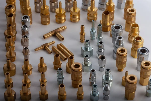 Açık gri arkaplana karşı pirinç hortum ve pnömatik parçaların çeşitliliği