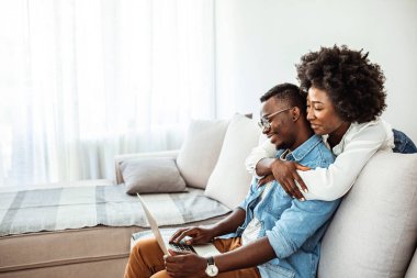 Mutlu Afrikalı çift dizüstü bilgisayar kullanıyor, internetten iyi haberler alıyor, e-posta alıyor, bankadan olumlu kararlar alıyor, karı-kocanın birlikte ekrana bakması, ipotek veya kredi onaylı kağıt mektubu.