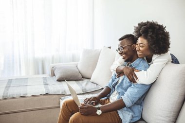 Aile, teknoloji, internet ve insanların konsepti. Evde dizüstü bilgisayarı olan mutlu bir çift. Evde dizüstü bilgisayar kullanan genç bir çiftin fotoğrafı.