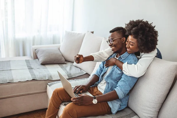 Evdeki kanepede dizüstü bilgisayar kullanan genç bir çiftin fotoğrafı. Koltuk sörfü onların en sevdiği hobi haline geldi. Evde dinlenirken dizüstü bilgisayar kullanan genç bir çiftin fotoğrafı.