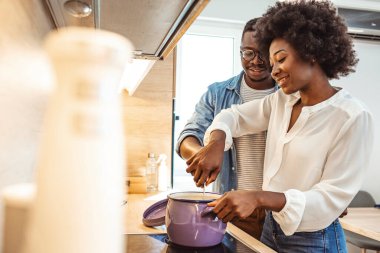 Çekici çift mutfakta yemek pişiriyor. Birbirinize bakıp gülümsüyorsunuz. Mutlu çift evlerinin mutfağında birlikte yemek pişiriyor. Siyah çift mutfakta yemek pişiriyor.. 