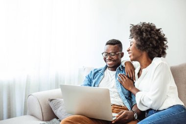 Genç siyah çift evdeki kanepede dizüstü bilgisayar kullanıyor. Dizüstü bilgisayarda film izleyen bir çift. Mutlu adam ve kadın kanepede dinleniyorlar. Boş vakitlerini evde geçiriyorlar..