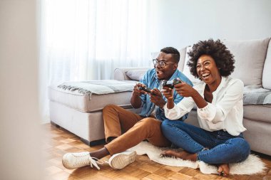Sanal gerçeklik gözlükleriyle video oyunu oynayan mutlu arkadaşlar yeni teknoloji konsoluyla eğlenen gençler. Genç Afrikalı Amerikalı çift oyun konsolunda joysticklerle oynuyorlar.