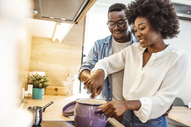 Çok ırklı bir çift evde öğle yemeği hazırlıyor. Sevgili siyah karı ve koca mutfakta yemek hazırlıyor. Mutlu aile, çatı katında vejetaryen yemekleri pişiriyor.