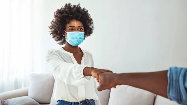 Male and female colleagues fist bumping, group of young business people with protective face masks. New normal greeting with fist bump. Two people wearing protective face mask and greeting with fist bump